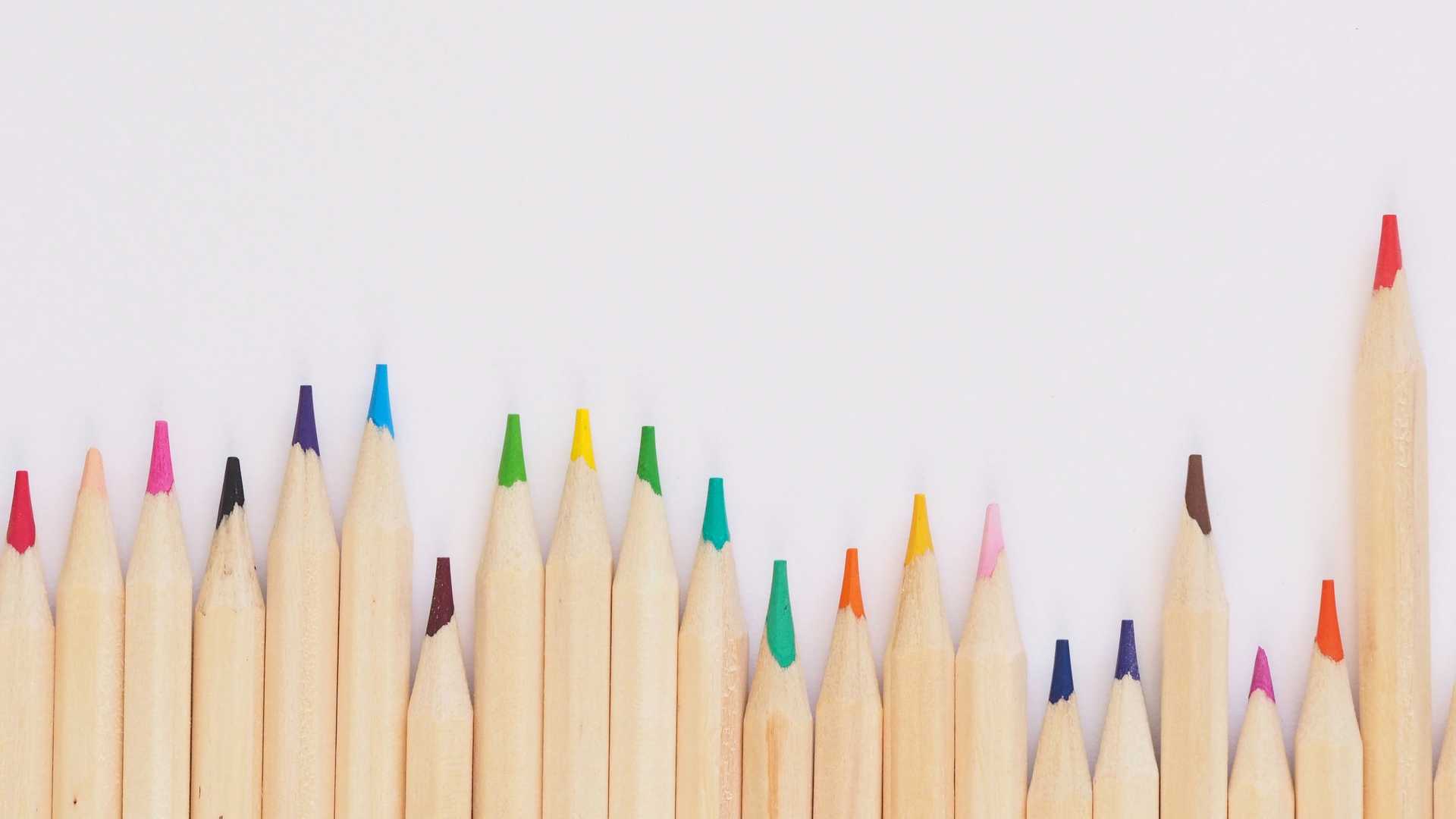 Colored pencil lined up on top of white surface